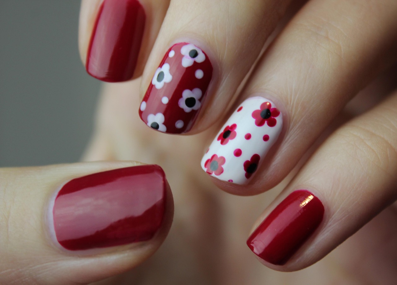 Diseño conceptual de uñas con flores en tonos rojos